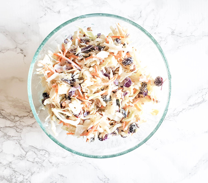 an overhead view of apple slaw in a glass bowl