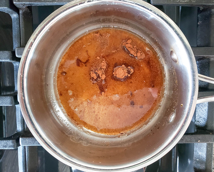 an overhead view of melted coconut oil in a pan with cinnamon and cayenne pepper in it.