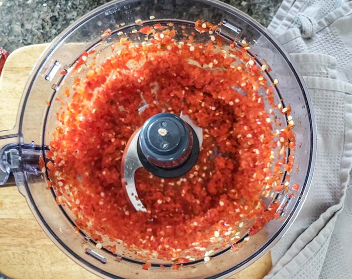 Chopped jalapeno peppers in a food procesor bowl.