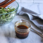 salad dressing mixed in a jar with a bowl of salad