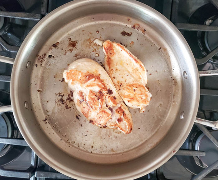 Boneless chicken breasts cooking in a skillet