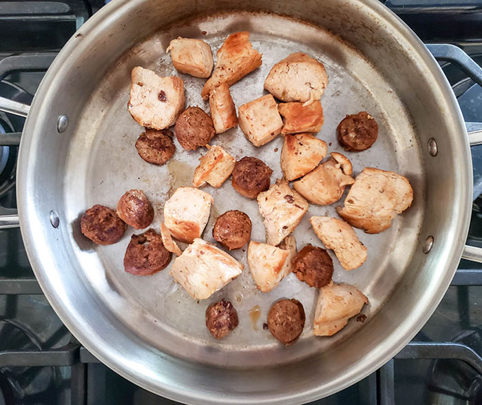 chicken and sausage cooking in a skillet