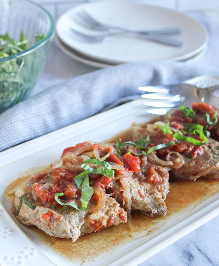 cooked boneless pork chops on a plage with a fork