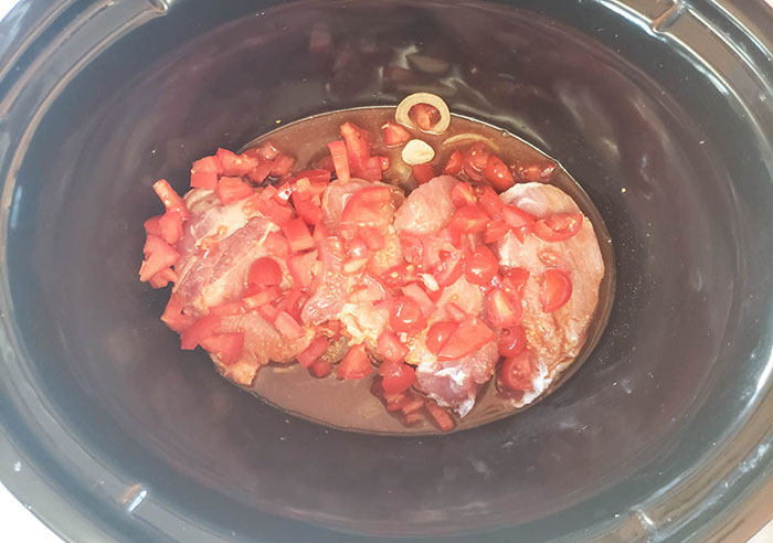 uncooked pork chops with tomatoes on top