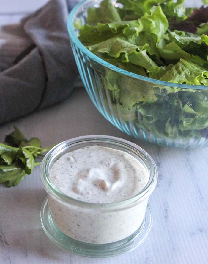 dressing in a jar with a salad in the background