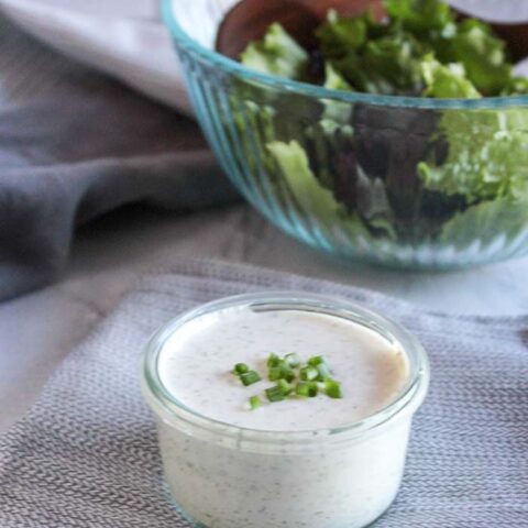 ranch dressing in a jar with a salad in the back