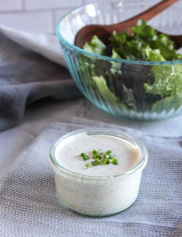 ranch dressing in a jar with a salad in the back