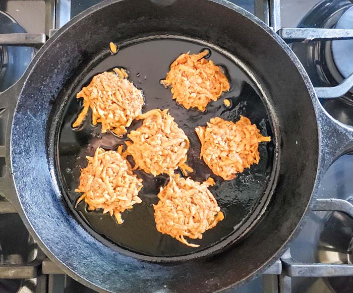 sweet potato fritters in a pan starting to cook