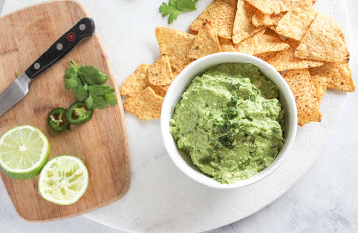 overhead view of guacamole in a bowl with chips