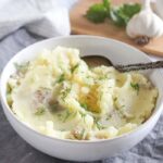 Mashed potatoes in a white bowl with butter and fresh dill