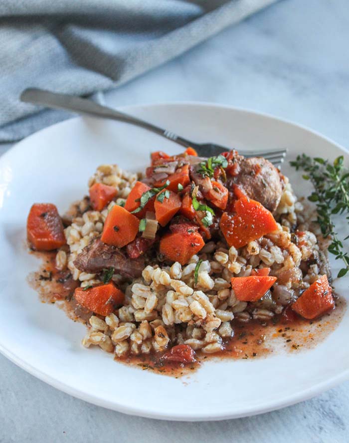 red wine chicken on a plate with a fork