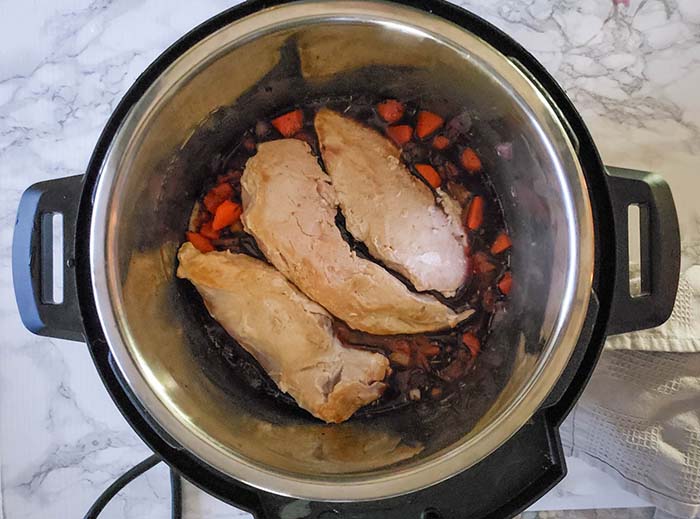 chicken breasts on top of veggies and wine in intant pot