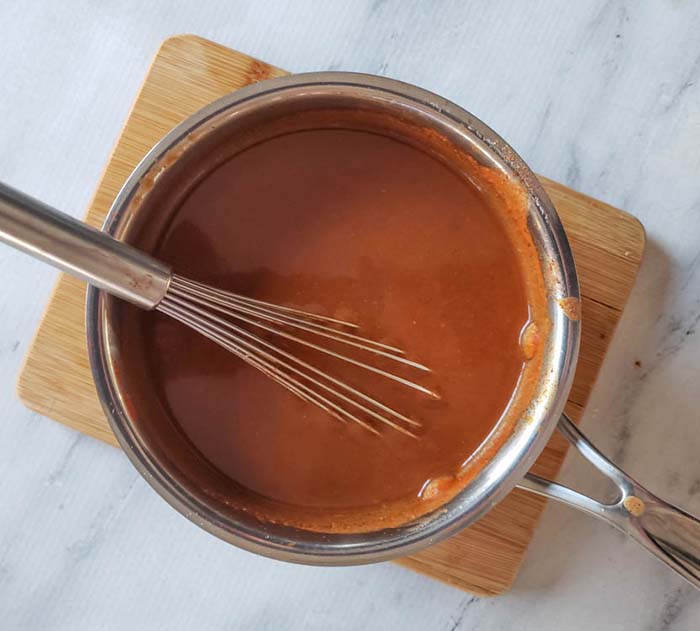 enchilada sauce in a pan with a whisk