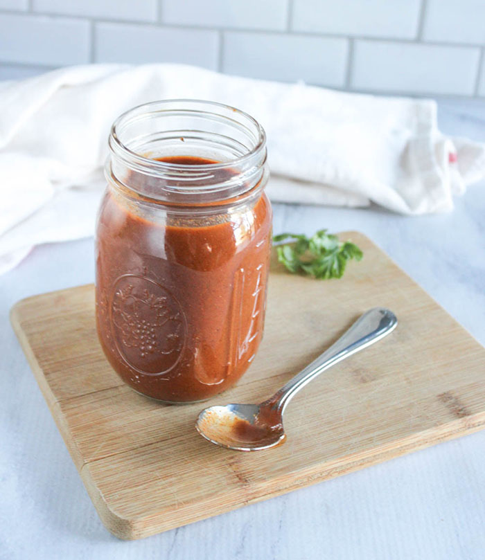 homemade enchilada sauce with a spoon on a cutting board