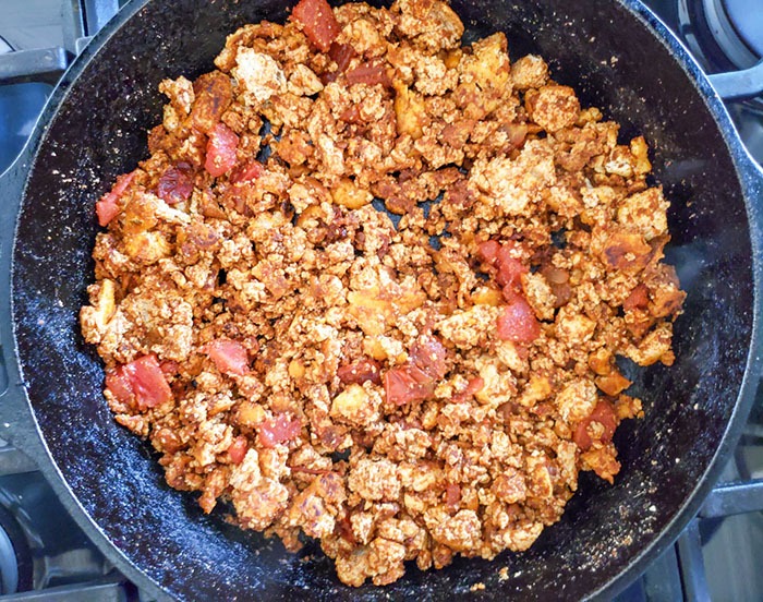 tofu crumbles in skillet cooked with tomatoes and spices