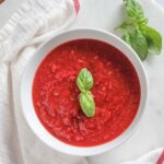an overhead view of marinara sauce with basil on top