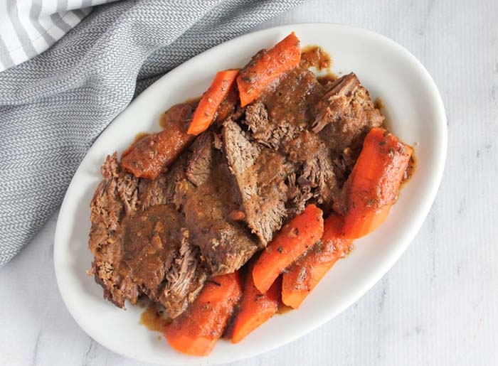 On overhead view of pot roast on a platter with carrots