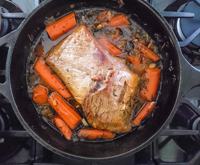 beef pot roast in a dutch oven with carrots cooked.