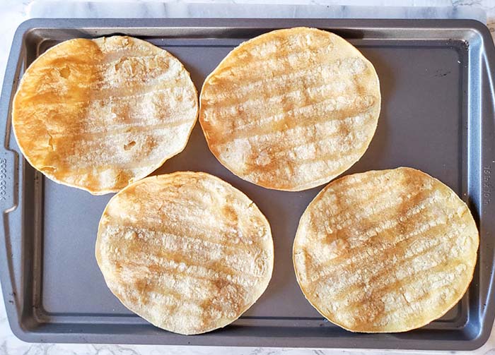 4 tortillas on a baking sheet