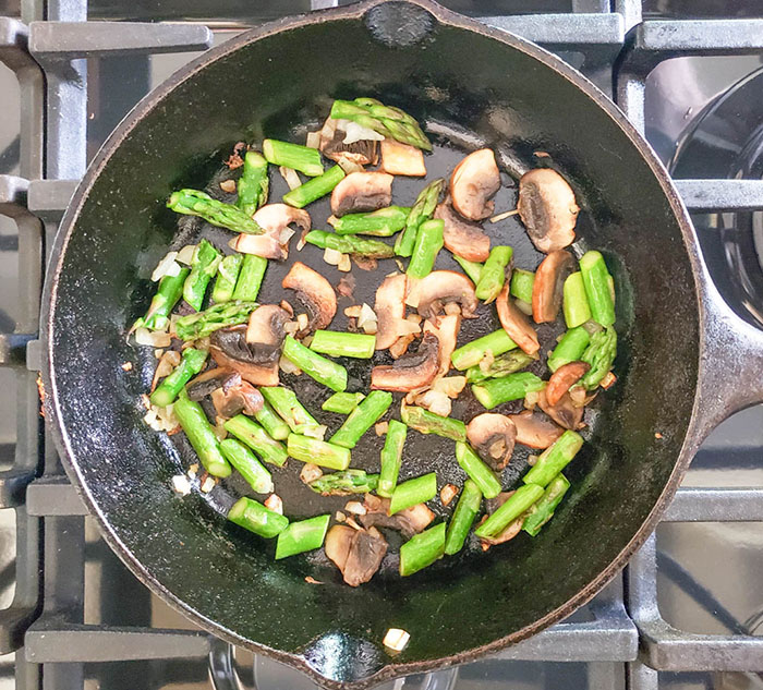 asparagus and mushrooms cooking in a skillet