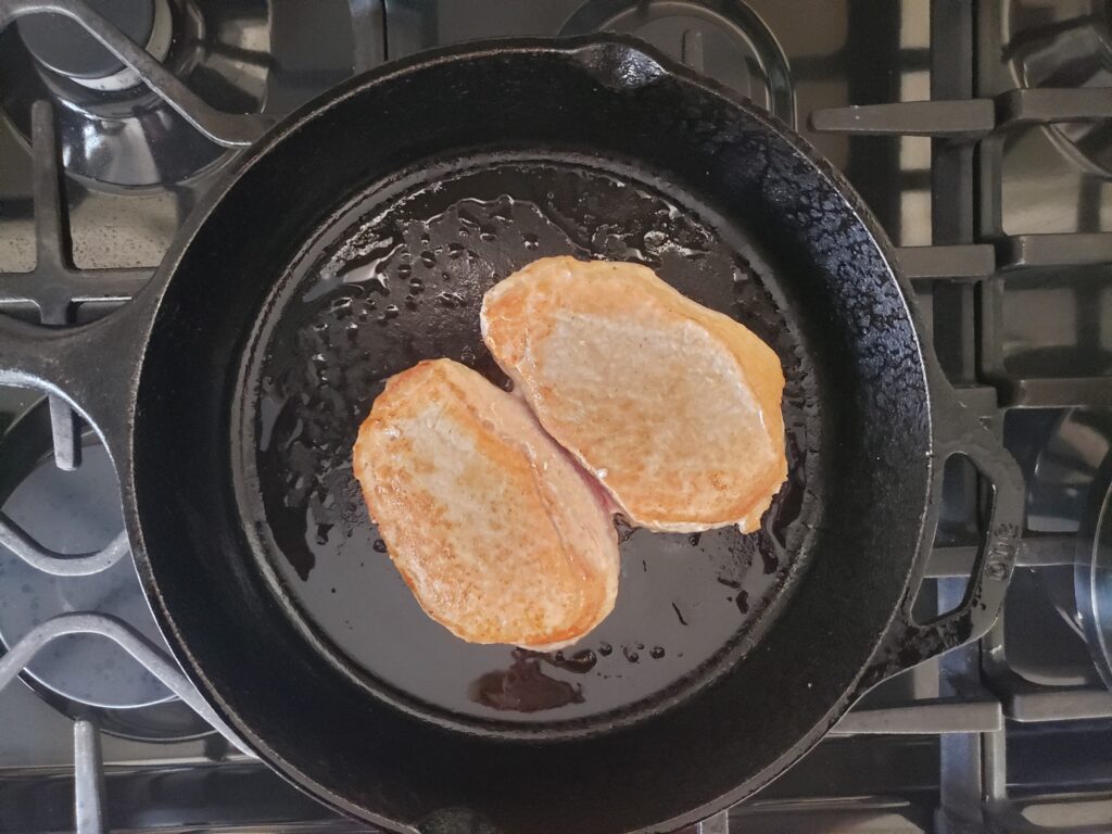 boneless pork chops searing in a skillet