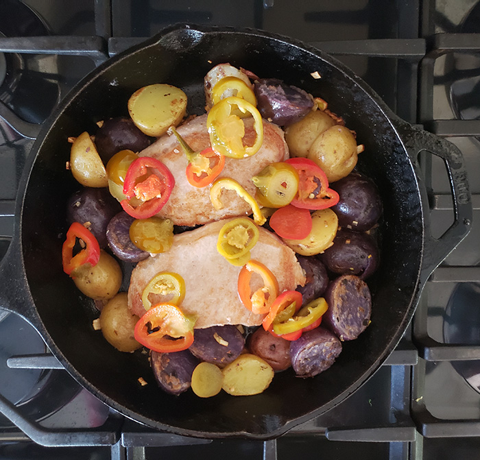 Pork Chops Potatoes and peppers in a skillet ready for oven