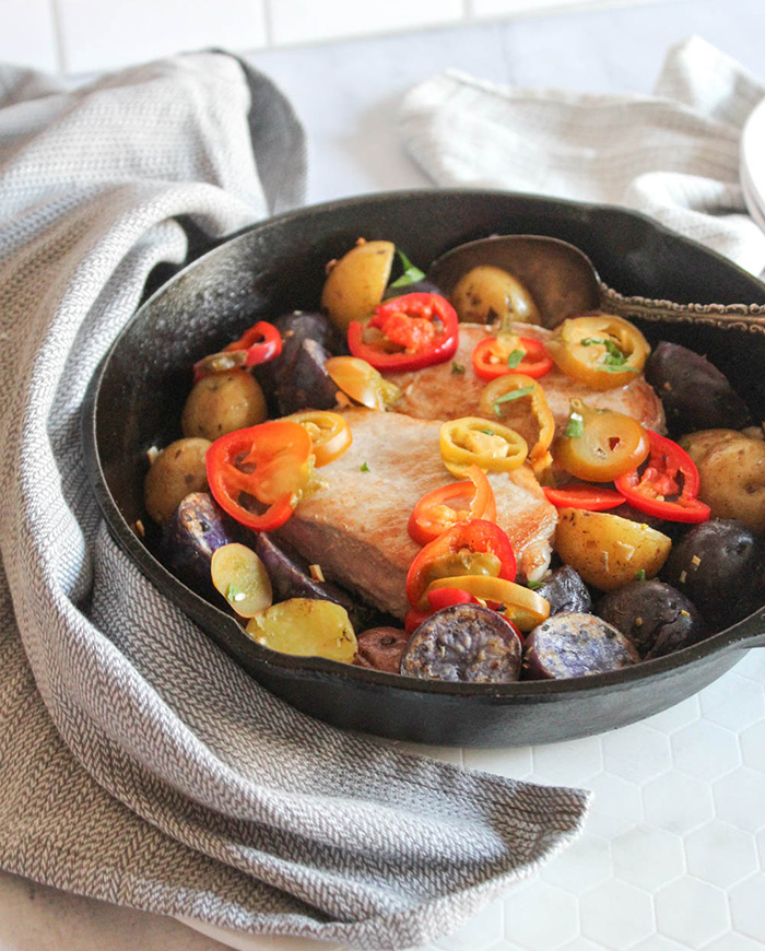 pork chops peppers and potatoes in a cast iron skillet