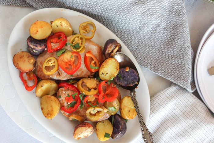 A view looking down at a plate of pork chops potatoes and peppers on a platter