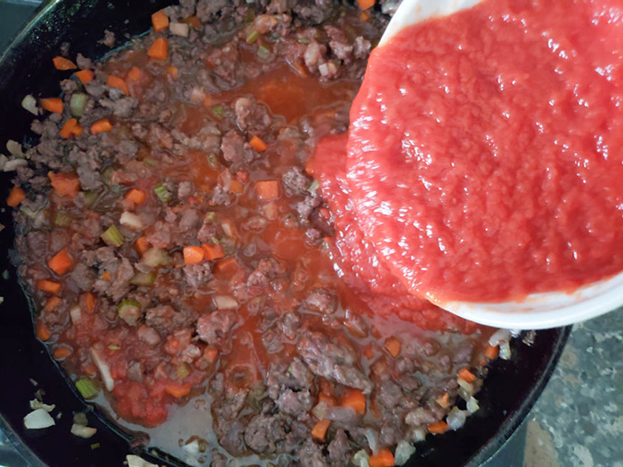 bolognese sauce tomatoes pouring in