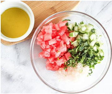 watermelon, cucumbers and herbs in a bowl.