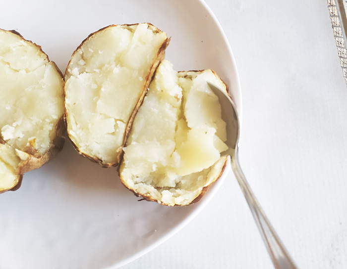 a spoon scooping out potato from skins