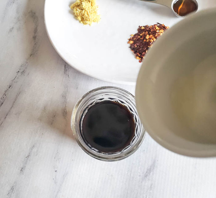 adding vinegar to stir fry sauce in jar