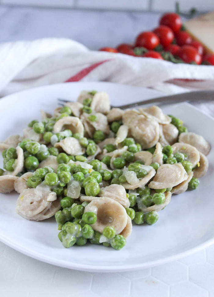 pasta and peas on a white plate with a fork