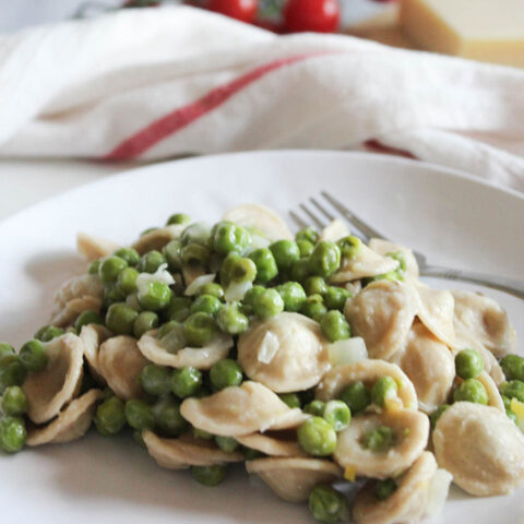 Pasta and peas on a plate with a fork