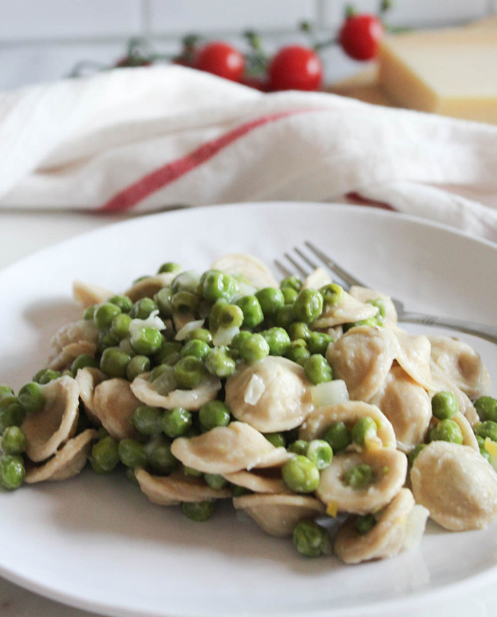 Pasta and peas on a plate with a fork