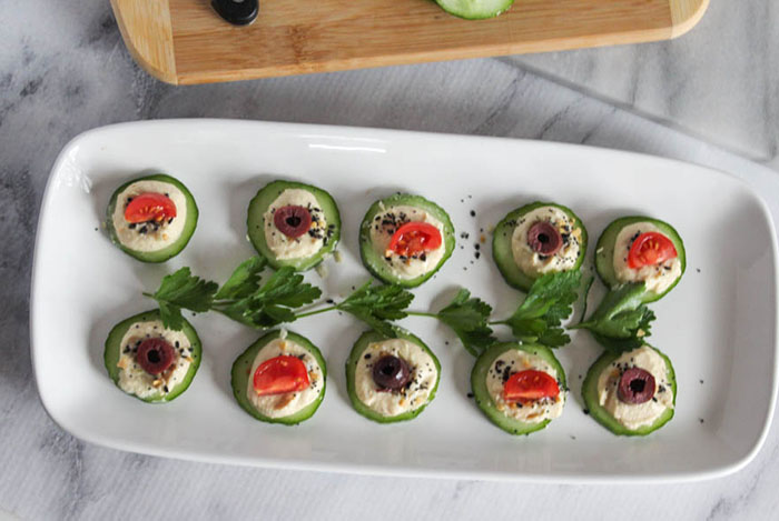 cucumbers with hummus and toppings on a platter