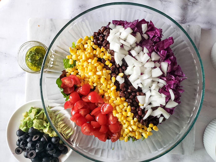 Salad topped with chopped tomatoes, corn, beans, onions cabbage