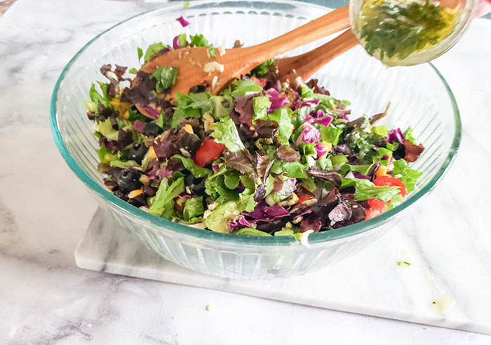 a photo of mexican chopped salad with dressing being added