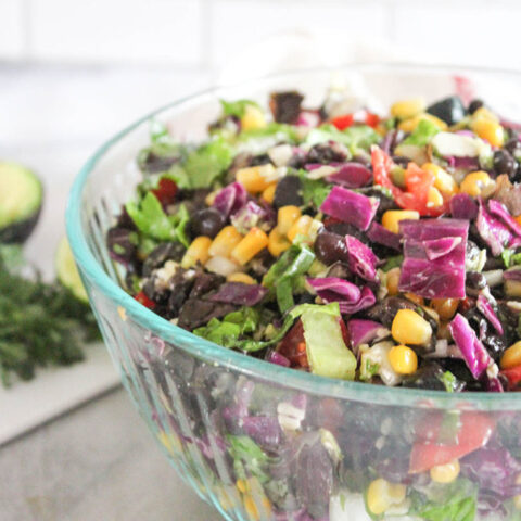 a close up of Mexican chopped salad in a glass bowl