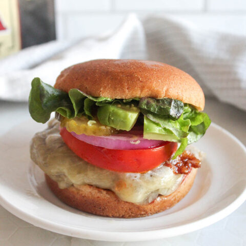 cheese burger with lettuce tomato onions on a roll