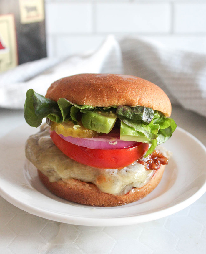 cheese burger with lettuce tomato onions on a roll