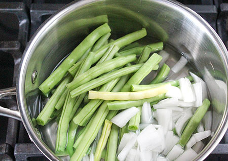 Green beans and onions in a pan not cooked