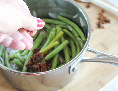 green beans onions in a pan with baking being added