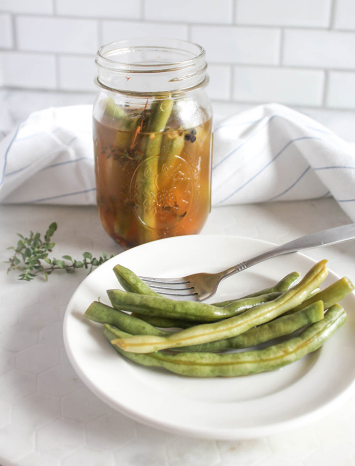 pickled green beans on a plate with a jar in the background