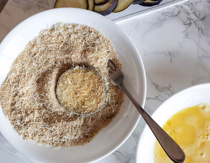 eggplant slice in bowl of bread crumbs
