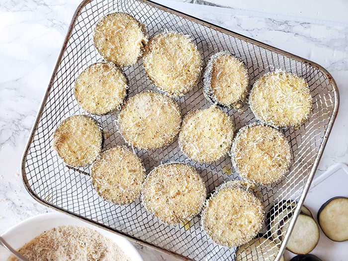 uncooked breaded eggplant in an air fryer basket