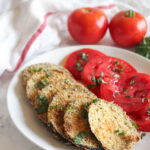 breaded eggplant on a plate with tomatoes on the side