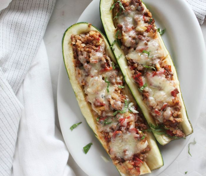 overhead view of zucchini stuffed zucchini on a platter with fresh herbs