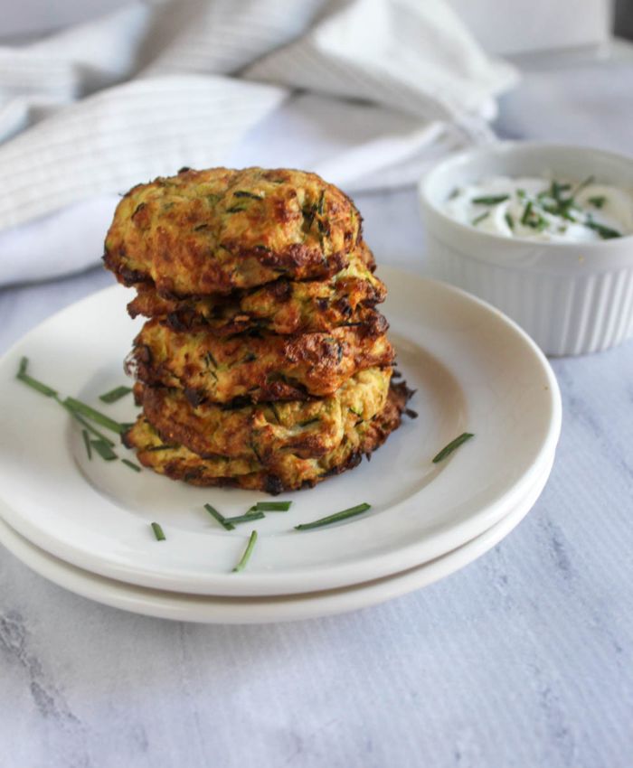 zucchini fritters stacked on a white plate