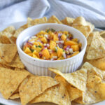 mango salsa with chips on a white plat